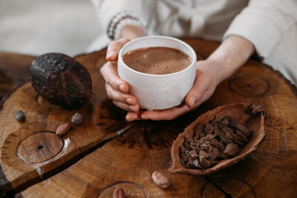 a hot cup of cacao, with the cacao fruit and seeds.