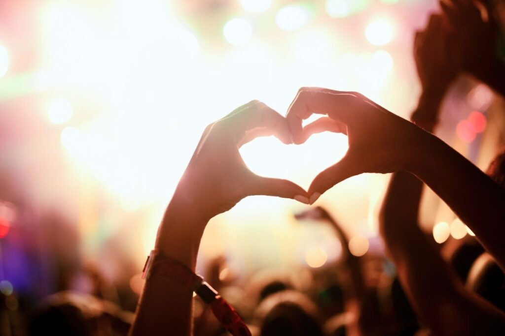 Hands holding up a heart sign at a music festival