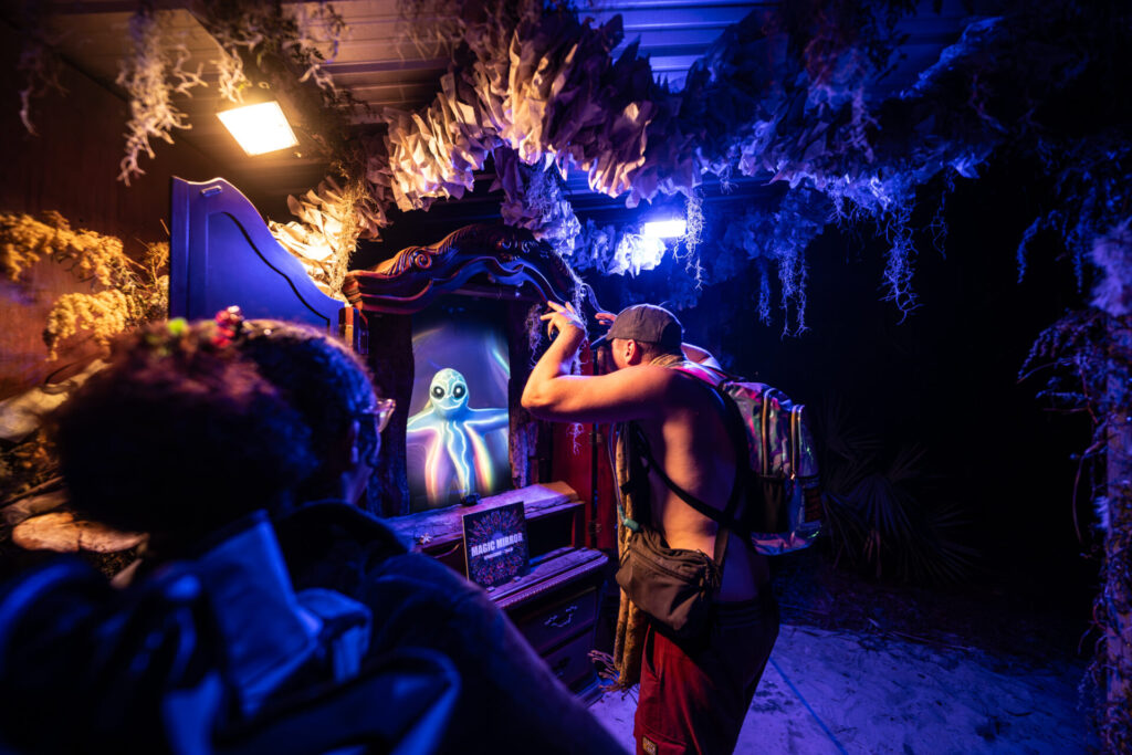 Patron interacting with a Magic alien creature at an art installment at Hulaween