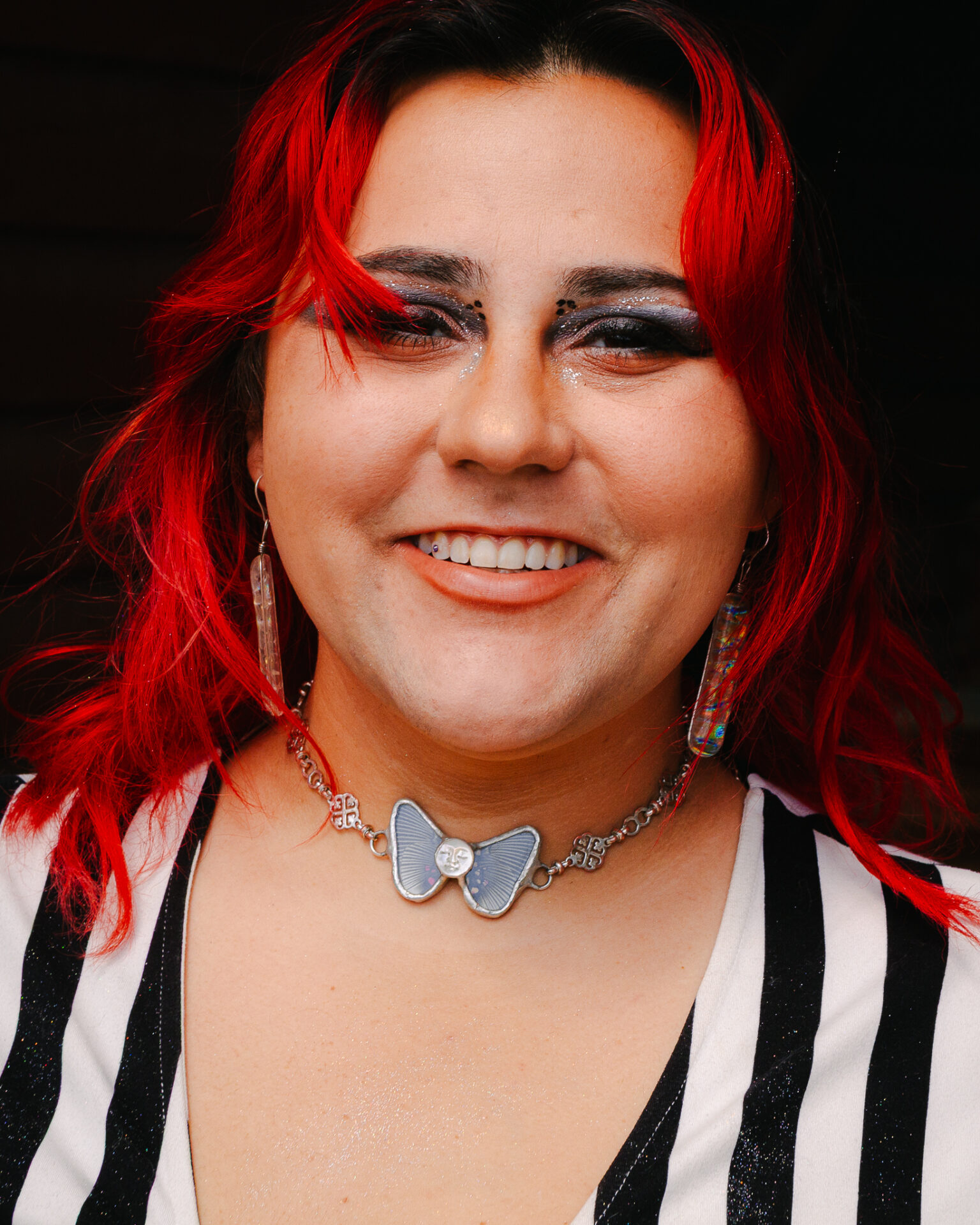 Portrait of Kendalyn Liebzeit in a butterfly necklace created by atomicbond glassworks smiling at camera